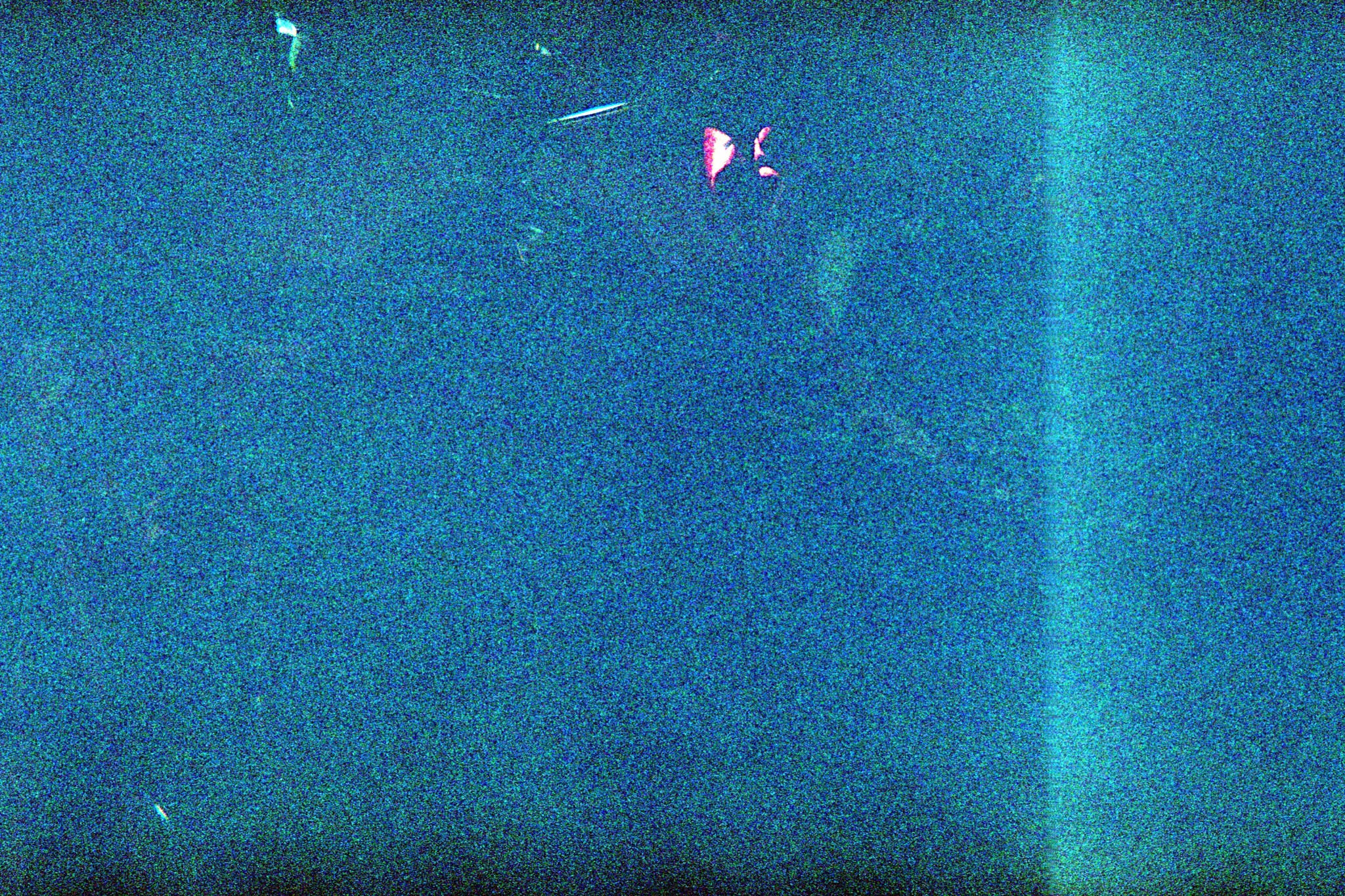 A small point of light suspended in a grainy blue field.