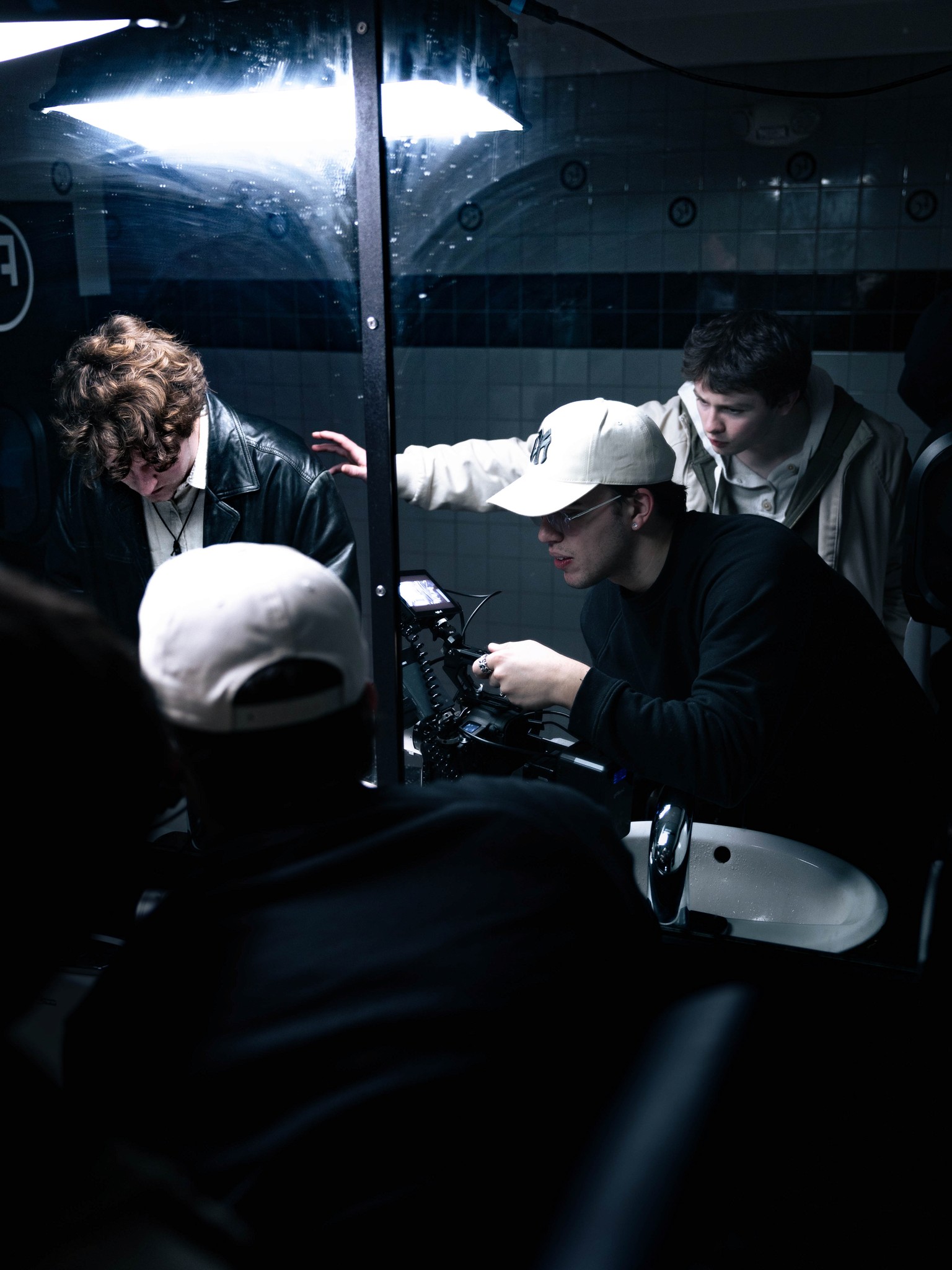A group gathered in a dark interior beneath a bright overhead light.