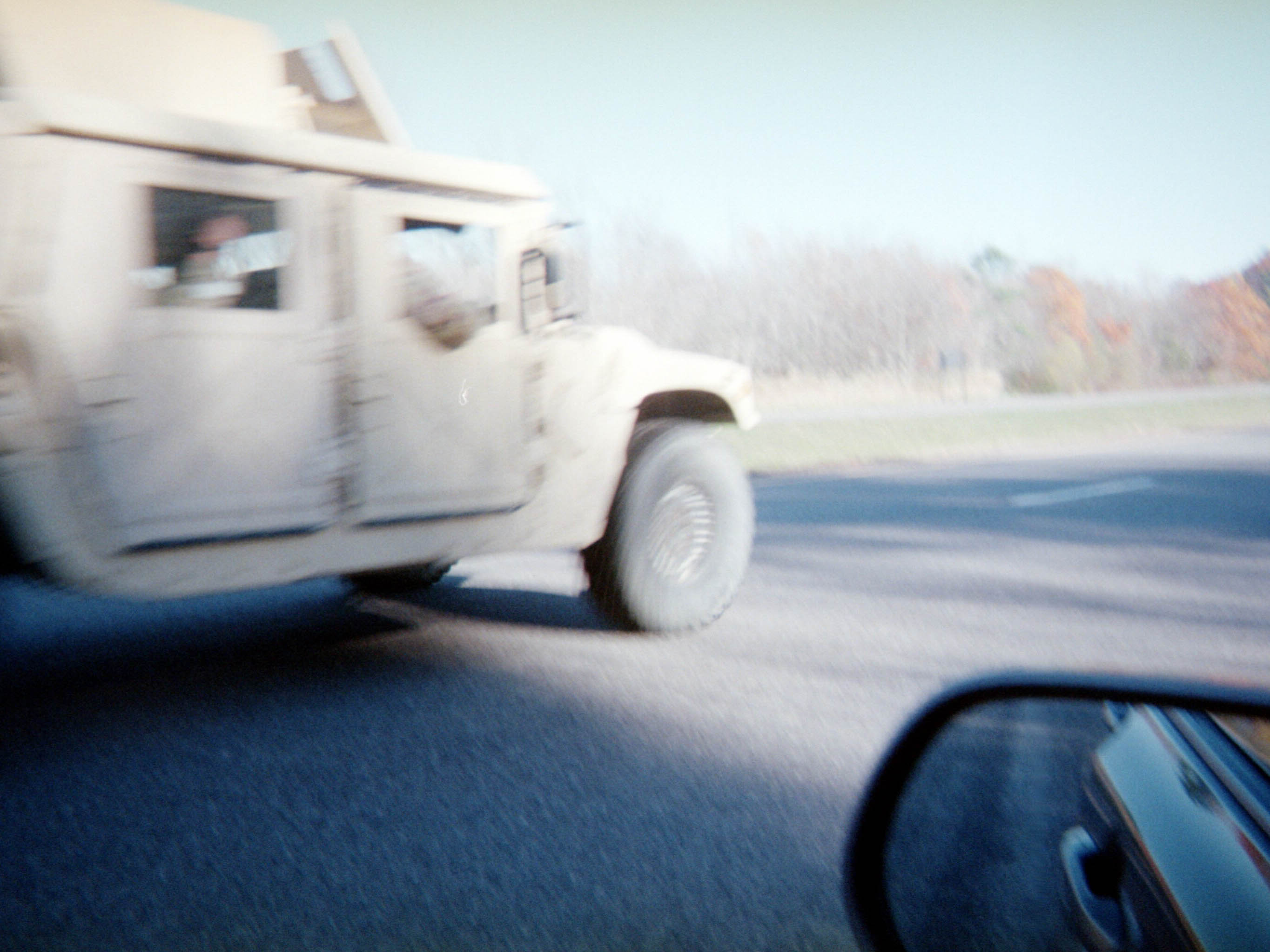 A moving vehicle seen through a car window, with the side mirror in frame.