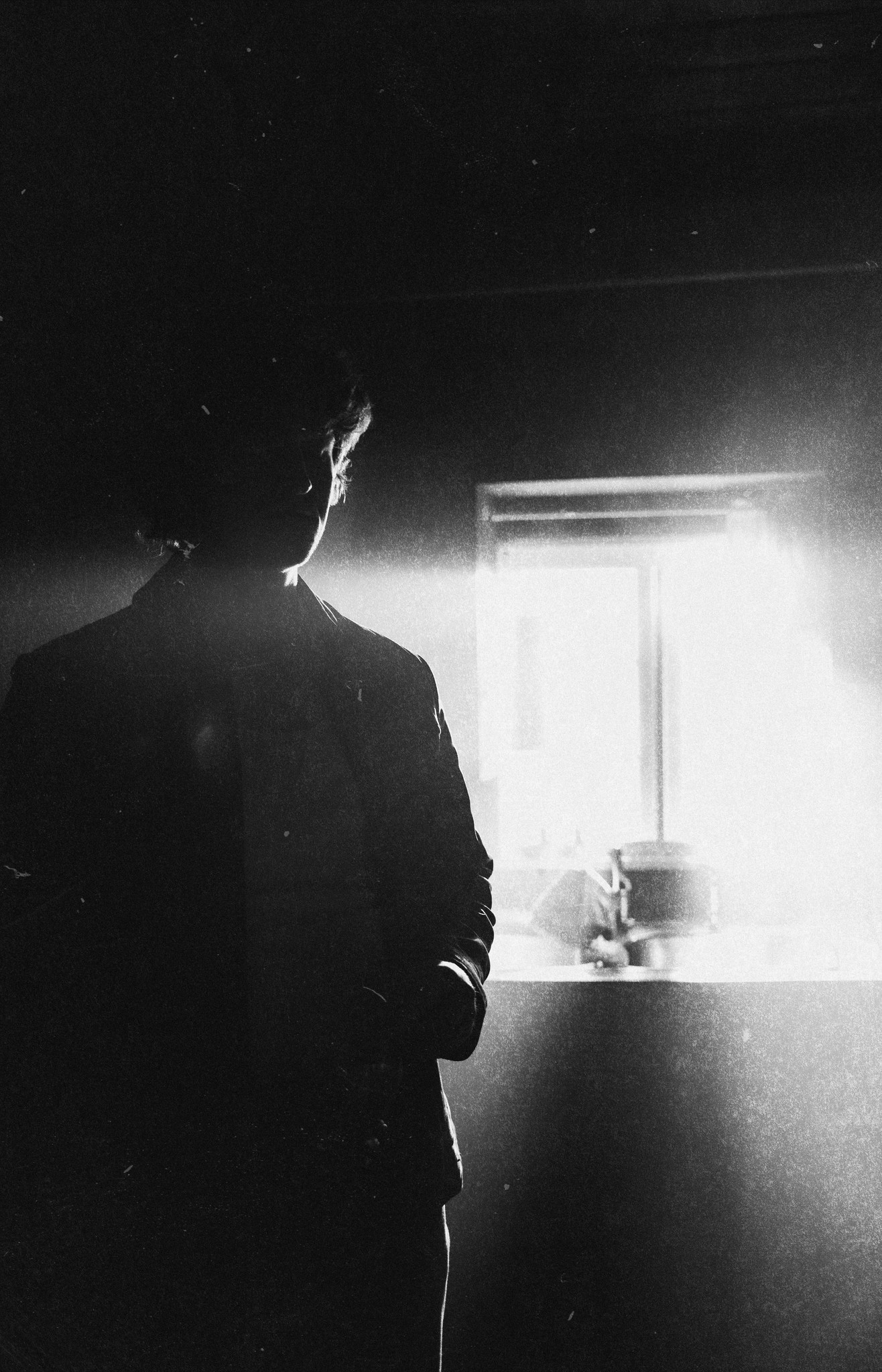 A black-and-white silhouette against a bright window and table lamp.